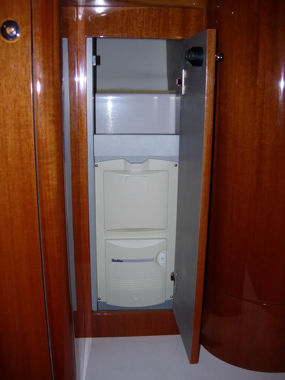 In a teak cabinet. An earlier SeaVac in a locker with its own door. Close it and the power unit disappears into the joinery.