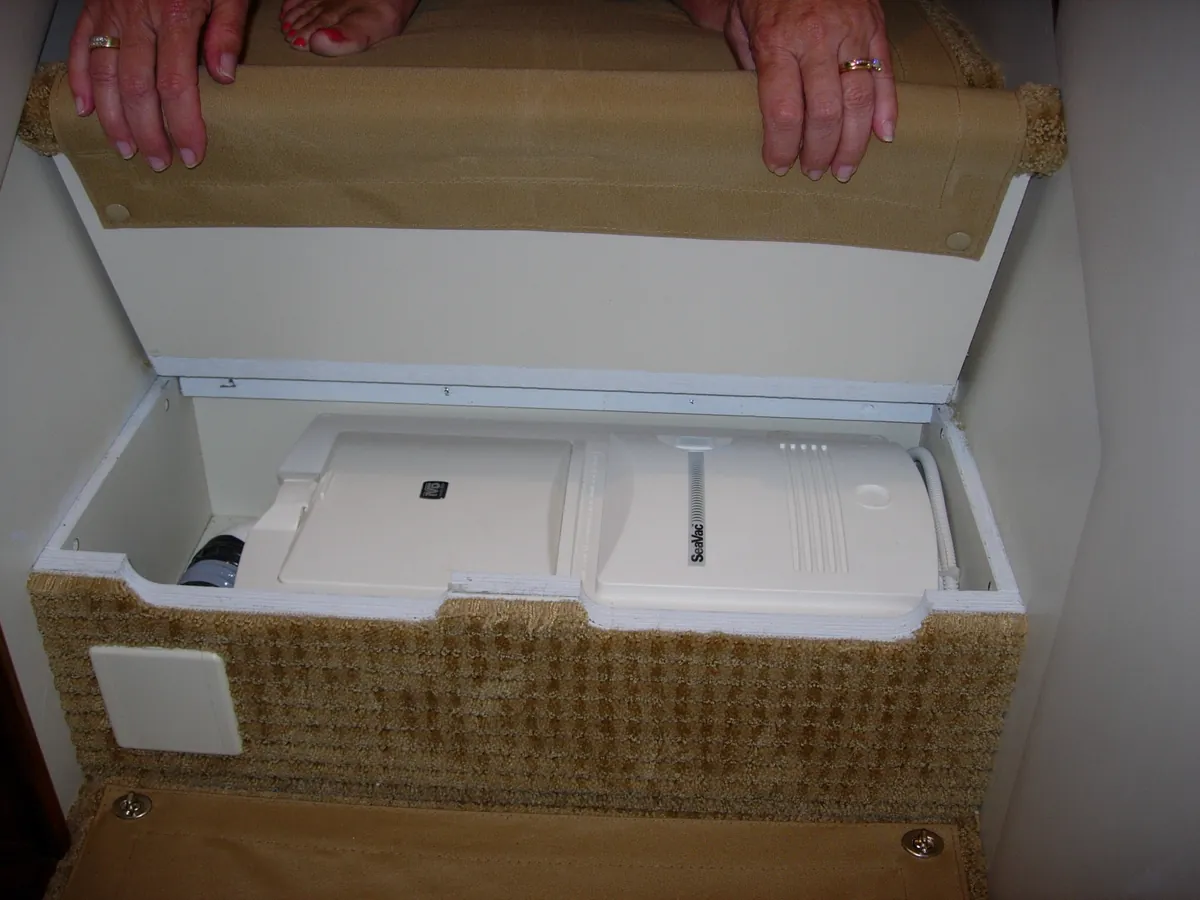 Under a companionway step. An RM-family unit in the dry space under a hinged step, the kind of spot most boats already have.